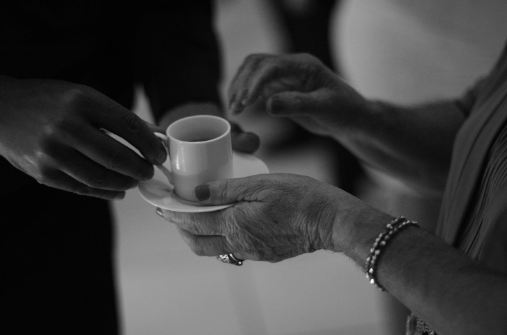 Eine jüngere Hand reicht einer älteren Person eine Tasse